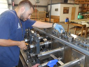 Factory worker moving metal through the rollers